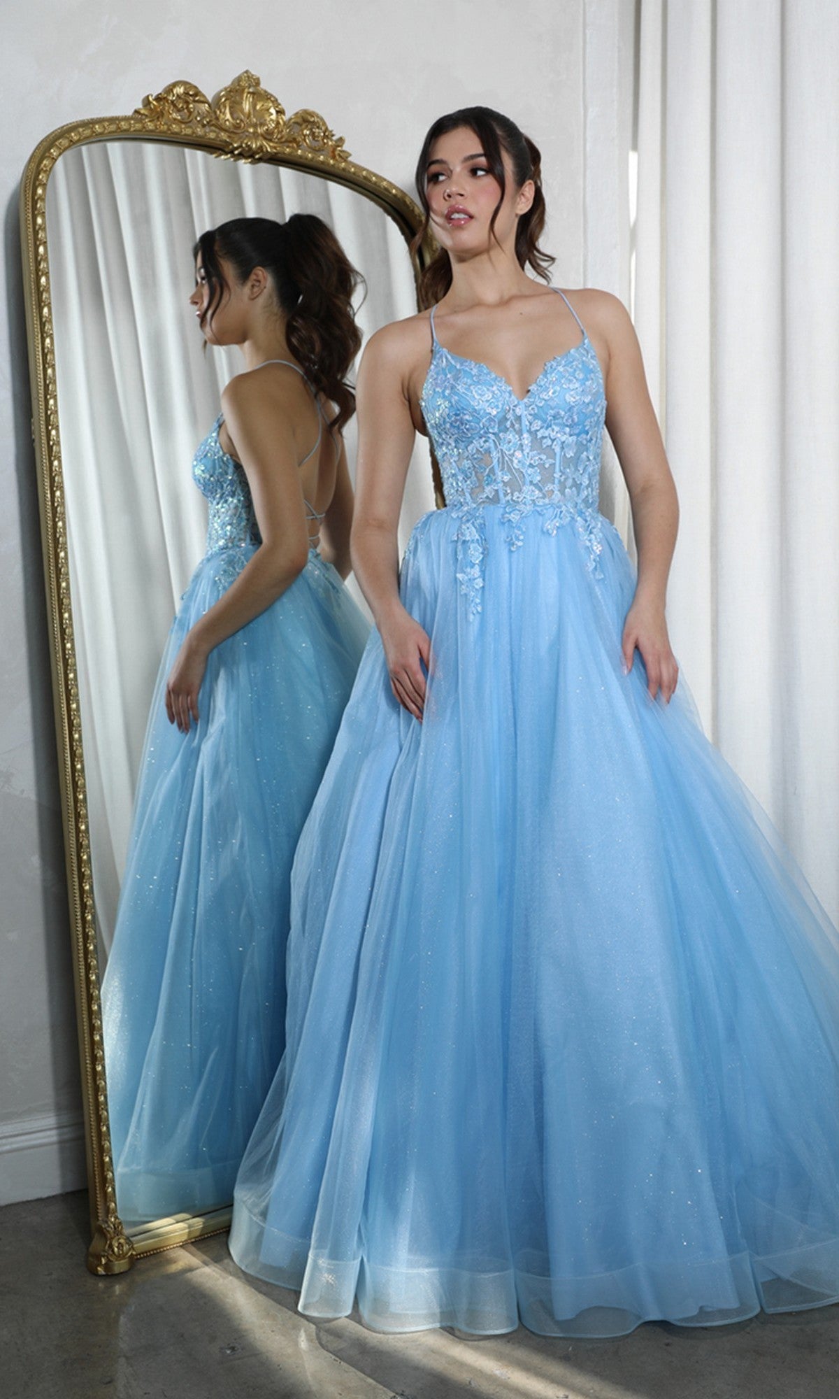 A woman in a blue Lace-Up Corset Long Prom Ball Gown (Eureka 9960) stands before a tall, ornate mirror, her reflection visible.